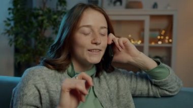 Neşeli öğrenci cep telefonuyla konuşuyor ve gülümsüyor. Evdeki kanepede dinleniyor.