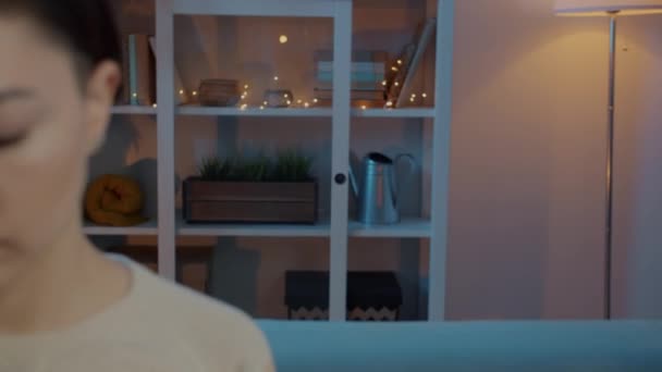 Збільшення жіночого фрілансера, що працює з ноутбуком, сидячи на дивані вдома вночі — стокове відео