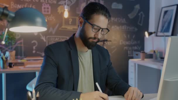 Hard-working employee writing then leaving office late at night — Stock Video