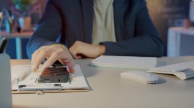 Karanlık ofiste bilgisayarla çalışan adam akıllı telefon kullanırken, iş adamlarının elinin yakın çekimi.