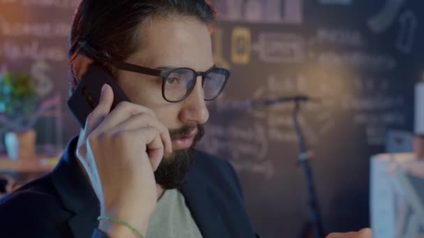 Karanlık ofiste cep telefonuyla konuşan genç işadamının eğik portresi. — Stok video