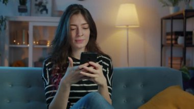 Akıllı telefon kullanan ve geceleri gülümseyen güzel bir genç bayan.