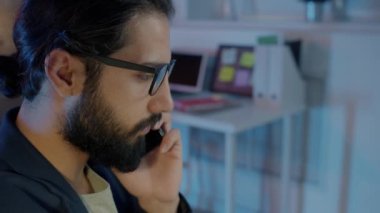 Motive olmuş iş adamının cep telefonuyla iş tartışan ve geceleri bilgisayar kullanan portresi.