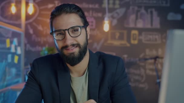 Портрет успешного предпринимателя, улыбающегося в освещенном офисе ночью — стоковое видео