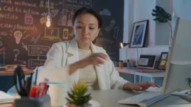 Bilgisayar kullanan ve geceleri kahve içen özel bir ofis çalışanı.