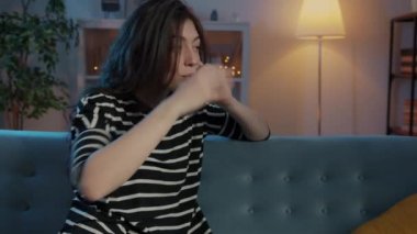 Neşeli kız cep telefonunda sohbet ediyor ve gülüyor. Evdeki koltukta oturuyor.