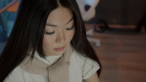 Close-up of cute Asian girl working in dark office typing with computer focused on job — Stok Video