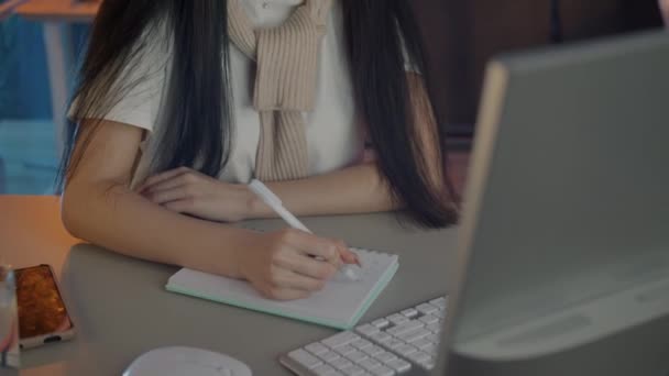 Asiático menina apoio ao cliente trabalhador falando usando fone de ouvido e tomar notas no escritório escuro — Vídeo de Stock