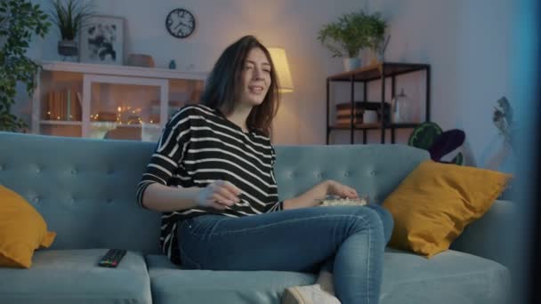 Menina alegre assistindo TV em casa rindo comer pipocas desfrutando de tempo de lazer — Vídeo de Stock