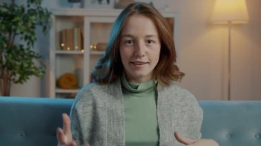Geceleri evdeki video görüşmesi sırasında konuşan ve el kol hareketi yapan güzel bir genç kadının portresi.