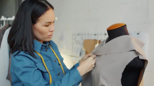 Pensive jovem mulher costura roupas da moda em alfaiates manequim trabalhando sozinho no estúdio — Vídeo de Stock