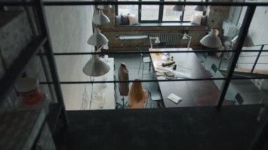 Genç bayan moda tasarımcısının modern giysiler üretmek için stüdyoya tek başına gelişinin en iyi görüntüsü.