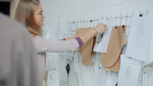 Muchacha atractiva modista elegir el material para la nueva ropa de trabajo en el estudio — Vídeos de Stock