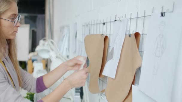 Pensieve naaister ontwerpt nieuwe kledingstukken en kiest stof die binnen in de studio werkt — Stockvideo