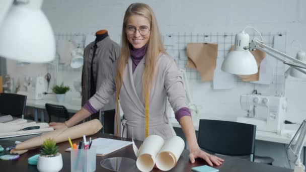 Schöne junge Frau Kleidungsdesignerin steht drinnen in Arbeitsplatz lächelnd in die Kamera — Stockvideo