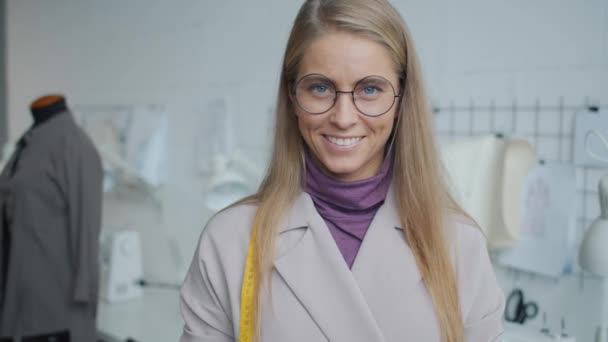Portrait of attractive young blonde seamstress standing in modern studio smiling looking at camera — Stock Video