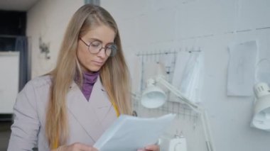 Modern stüdyoda çalışırken giysi tasarımcılarının çizimlerini yavaş çekimde asmaları.