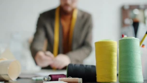 Rysunek projektanta mody w pracowni krawieckiej przy stole roboczym z materiałami do szycia — Wideo stockowe