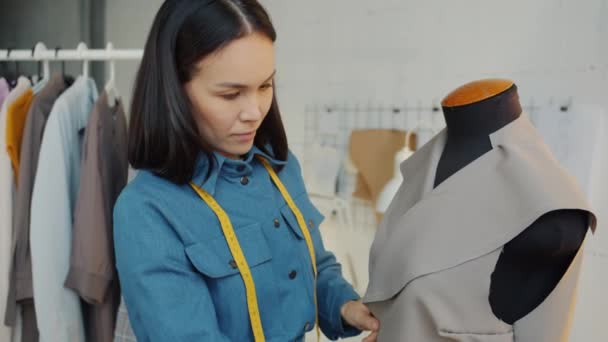 Young woman making new clothes on tailors dummy then turning to camera and smiling — Stock Video