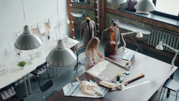 Vedere de top a croitorilor bărbat și femeie care lucrează în studio vorbind făcând articole de îmbrăcăminte noi — Videoclip de stoc