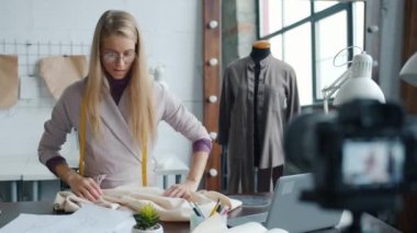 İnternet vlog 'u için video kaydeden genç kadın terzi kamera kullanarak skeçleri konuşuyor ve gösteriyor