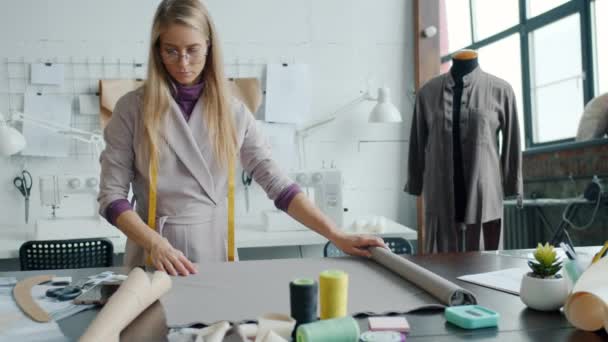 Slow motion of young lady clothes designer working at table drawing on fabric focused on creative activity — Stock Video