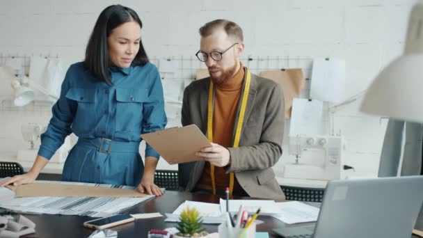 Vrouwelijke en mannelijke kleermakers die creatieve ideeën uitwisselen op de werkplek — Stockvideo