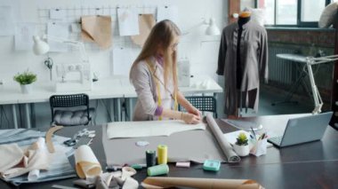 Kıyafet tasarımcısı, modern stüdyoda tek başına çalışan malzemeler üzerine yeni elbiseler dikiyor.