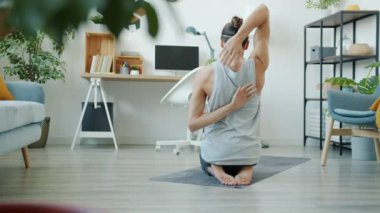 Kas yığını genç bir adamın kollarını açması yoga minderinde oturması evde tek başına egzersiz yapması.