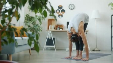 Evde tek başına güneşlenme kompleksi eğitimi alan yetenekli yoga öğrencilerinin yavaş çekimleri.