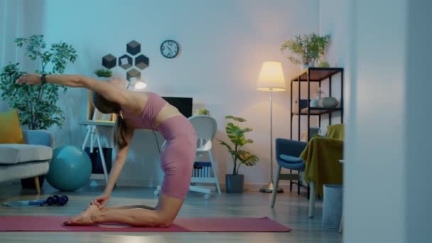 Porträtt av flexibel idrottskvinna som tränar stretching ensam hemma på natten — Stockvideo