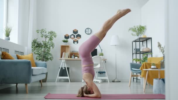 Porträt eines attraktiven Mädchens beim Kopfstand, das zu Hause Yoga-Übungen macht — Stockvideo