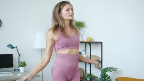 Ritratto inclinato di donna snella che si allena con corda da salto in casa — Video Stock