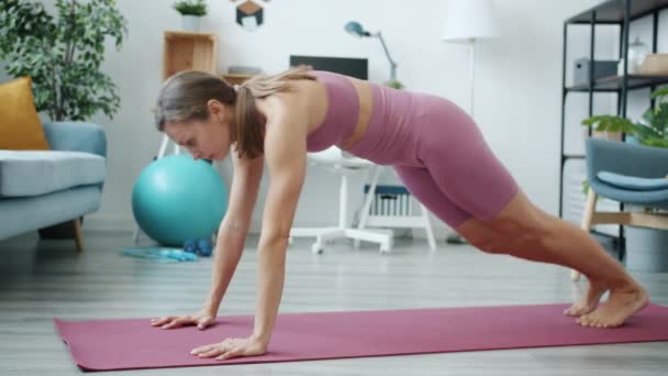 Sidovy av motiverade idrottskvinna motionerar inomhus koncentrerad på fysisk aktivitet — Stockvideo