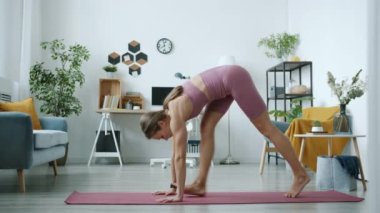 Esnek yoga öğrencisinin yavaş çekimde çekilmiş portresi. Bacağı ayrılmış, sonra evde yengeç duruşu eğitimi alıyor.