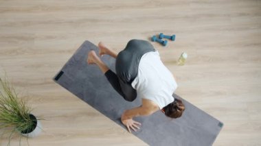 Sporcunun yoga minderinin üstünde amuda kalkarak stüdyoda antrenmanların keyfini çıkarması.