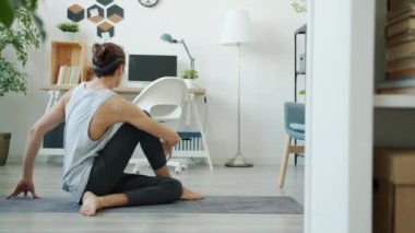 Evde yoga yapmaktan zevk alan esnek bir gencin ağır çekim hareketi.