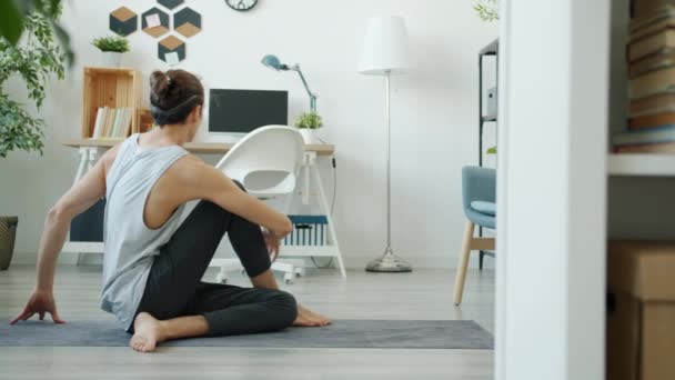 Movimento lento de jovem flexível fazendo reviravoltas corporais curtindo ioga em casa — Vídeo de Stock