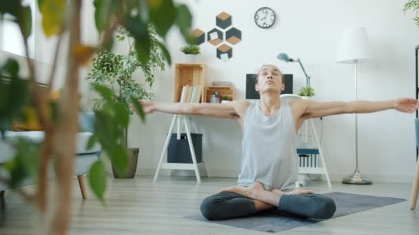 Rallentatore del giovane flessibile che pratica yoga piega in posizione loto a casa — Video Stock