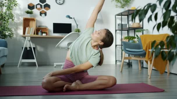 Ritratto al rallentatore di giovane donna snella che fa esercizio yoga in posizione loto in appartamento — Video Stock