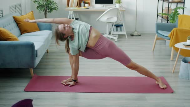 Gerakan lambat dari latihan wanita muda yang fleksibel di rumah melakukan yoga pada tubuh peregangan tikar — Stok Video