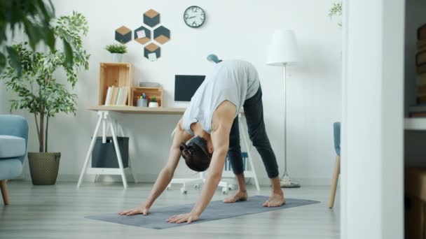 Wolny ruch faceta robi kompleks jogi asany trening sam w mieszkaniu — Wideo stockowe