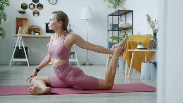 Retrato de linda chica estirando cuerpo haciendo yoga asanas en interiores en apartamento — Vídeos de Stock