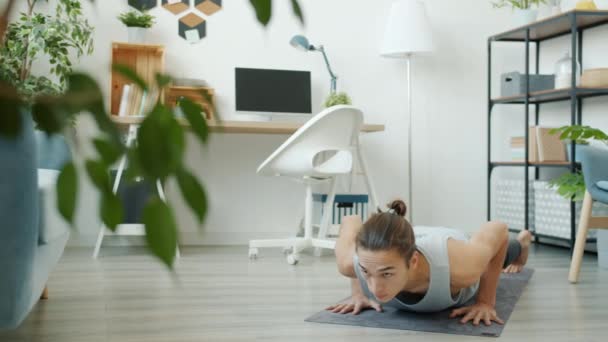 Powolny ruch młodego mieszanego studenta rasy robi jogę asanas w mieszkaniu — Wideo stockowe