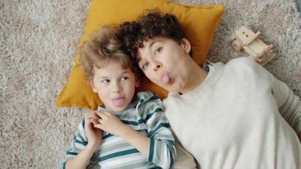 Портрет счастливой семьи мама и ребенок веселятся делая смешные лица смеясь над домом — стоковое видео