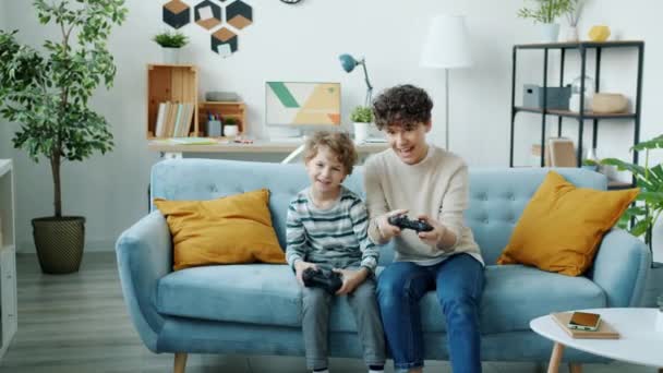 Retrato de criança jogando videogame com os pais usando joysticks se divertindo em casa — Vídeo de Stock