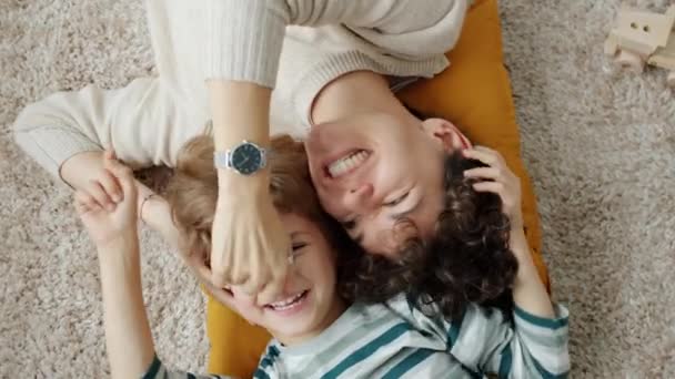 Vista superior de la madre y el niño riendo jugando a divertirse tumbado en el suelo en casa — Vídeo de stock