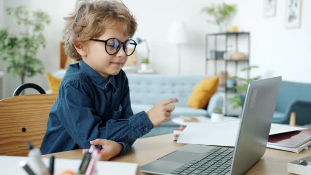 Poważne dziecko podejmowania rozmowy wideo online pokazując wykresy biznesowe z laptopem rozmowy i gestykulacji — Wideo stockowe