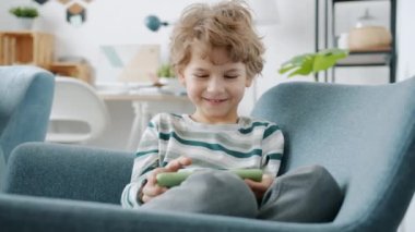 Mutlu küçük çocuk video oyunu oynuyor. Apartmanda akıllı telefonla eğleniyor.