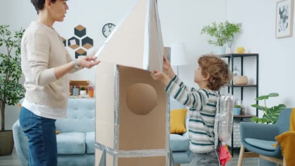 Slow motion van jonge vrouw en kind het maken van kartonnen ruimteschip thuis — Stockvideo
